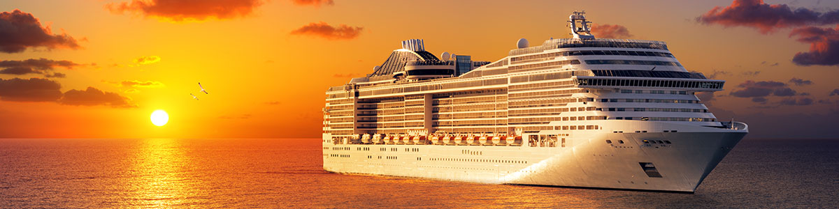 A large cruise ship is in the ocean at sunset.