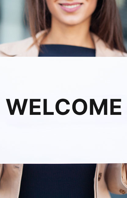 A woman holding up a sign that says " welcome ".